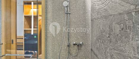A modern bathroom with a freestanding shower, a glass door, and a marble countertop.