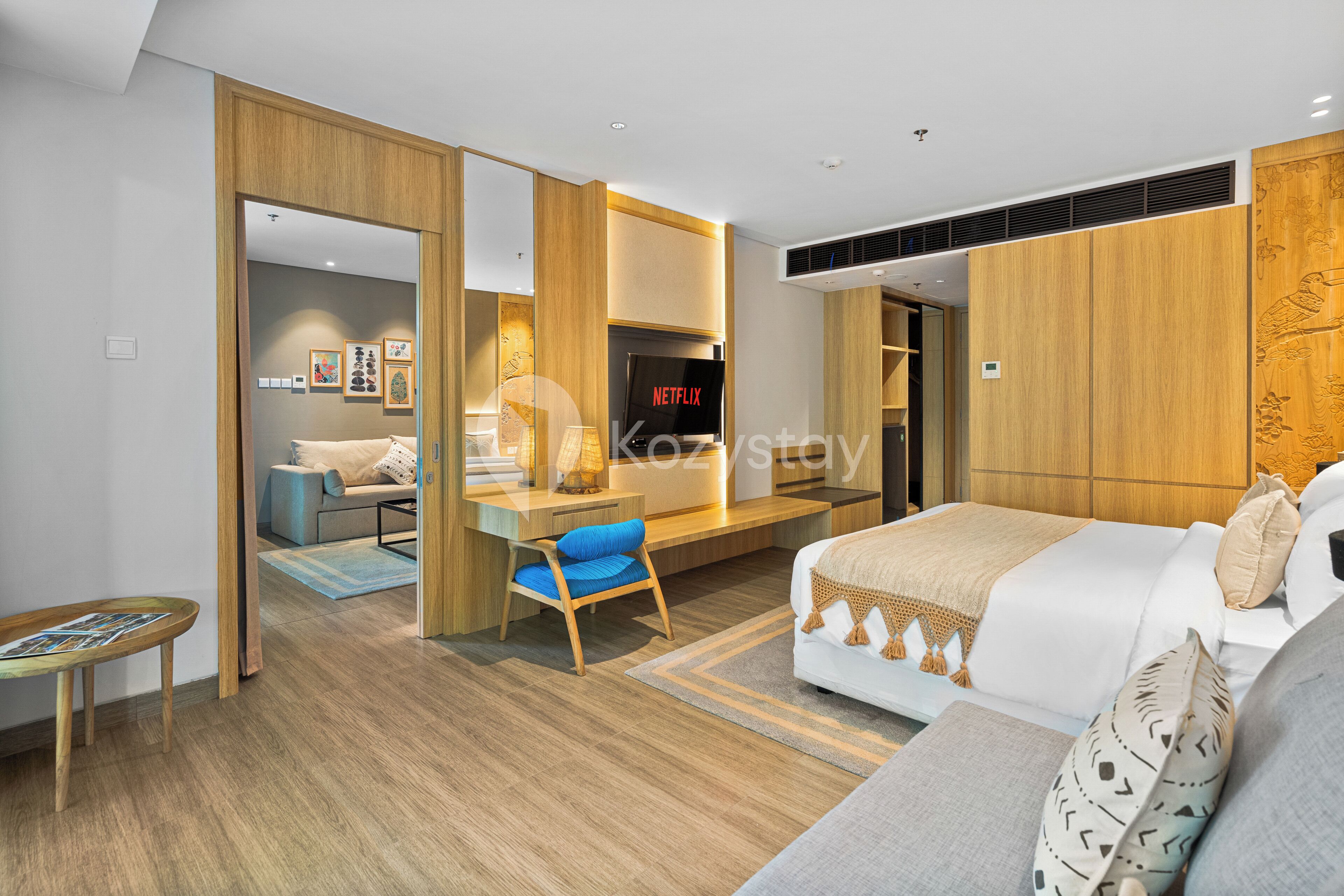 A modern hotel room with a bed, a desk, and a TV displaying 'NETFLIX'.
