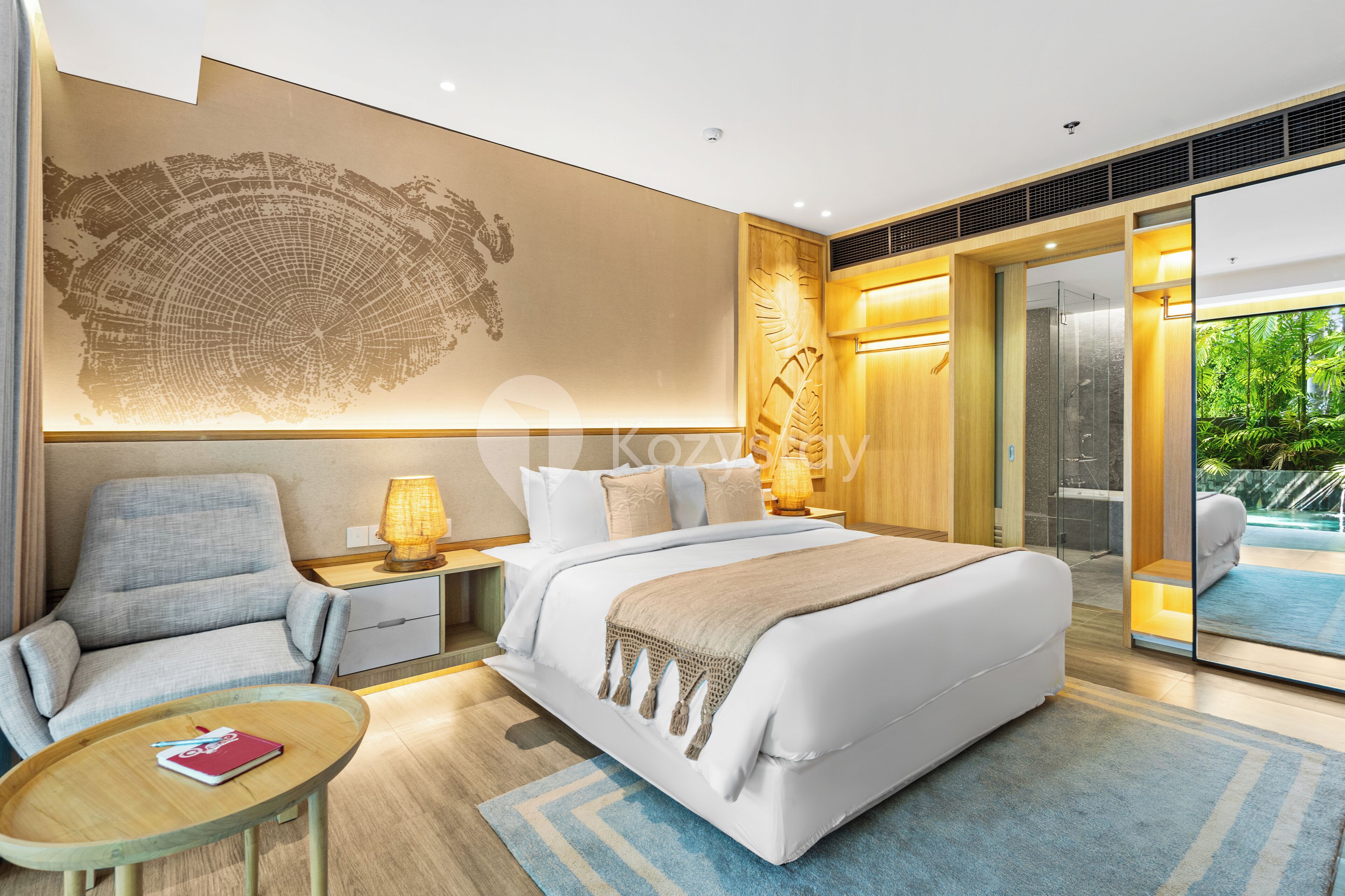 Une chambre d’hôtel moderne dotée d’un grand lit, d’un coin salon avec une table et d’une vue sur la piscine, visible à travers la porte vitrée.