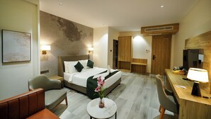 A modern hotel room with a large bed, a desk, a chair, and a small table with a vase of flowers. - Hotel Park Inn Nellore - Near the Hospital & Highway (Nellore)