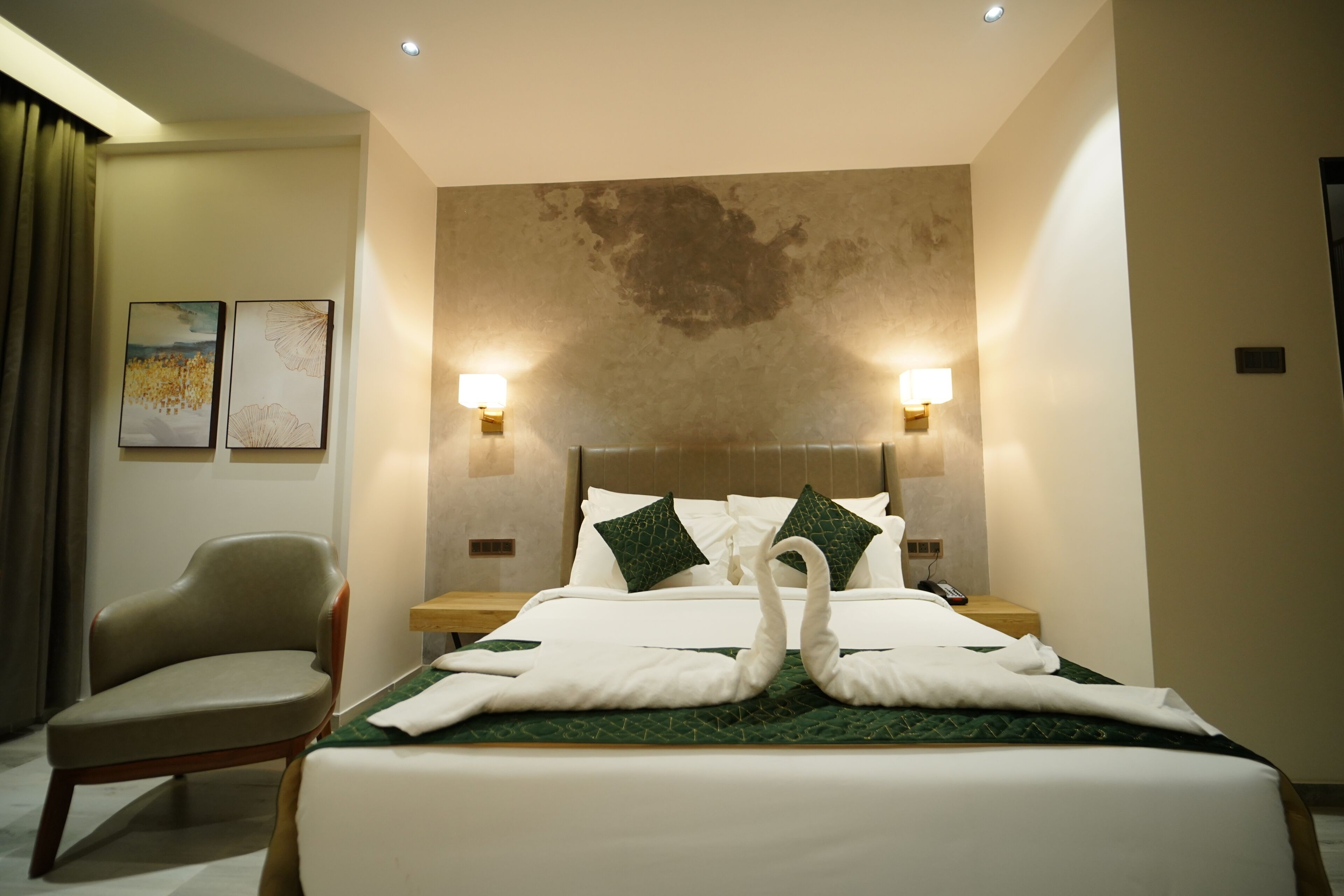 A hotel room with a neatly made bed, two wall-mounted lamps, a chair, and artwork on the wall.
