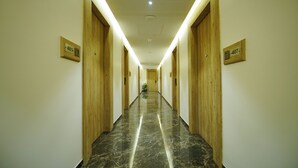 A hotel hallway with wooden doors and marble flooring. - Hotel Park Inn Nellore - Near the Hospital & Highway (Nellore)