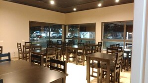 A dining area with multiple tables and chairs, large windows with a view of the street, and a modern interior design.