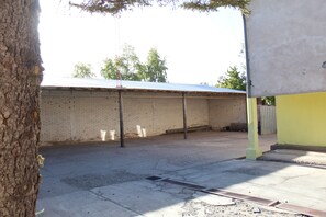 A brick building with a metal roof, a tree, and a concrete floor.