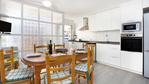Una cocina moderna con armarios blancos, una mesa de comedor con sillas y un ventanal grande.