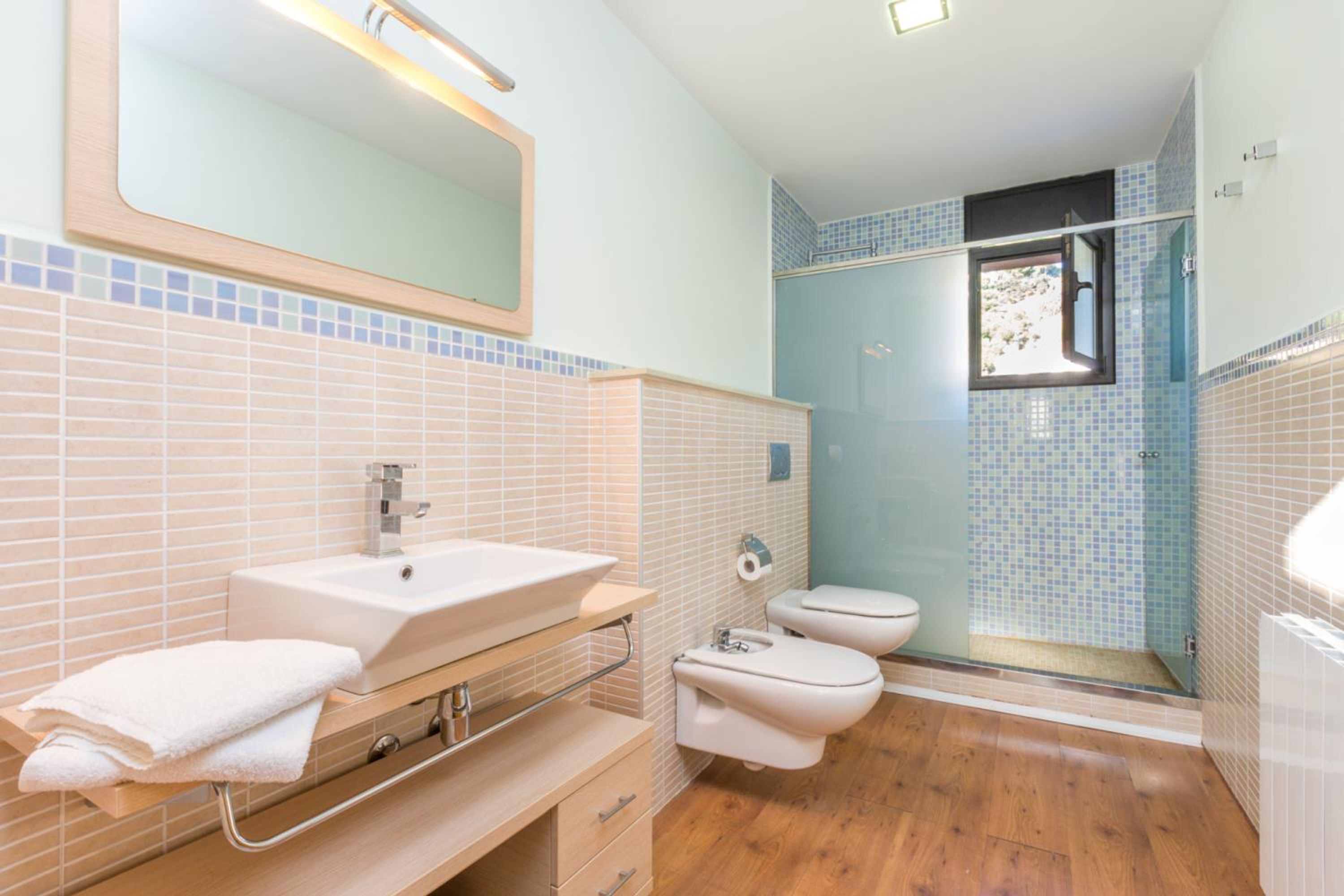 Un baño con lavamanos, espejo, inodoro y ducha.