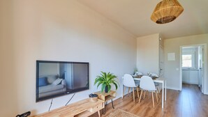 A modern living room with a flat-screen TV, wooden bench, dining table with chairs, and a hanging light fixture. - Costa Brava E-4 in Calella de Palafrugell (Palafrugell)