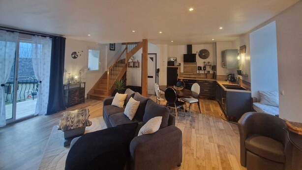 A spacious living room with a staircase leading to a kitchen area.