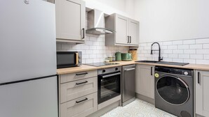 A compact kitchen with a refrigerator, oven, microwave, sink, and dishwasher. - The Annick Suite No.1 (Irvine)