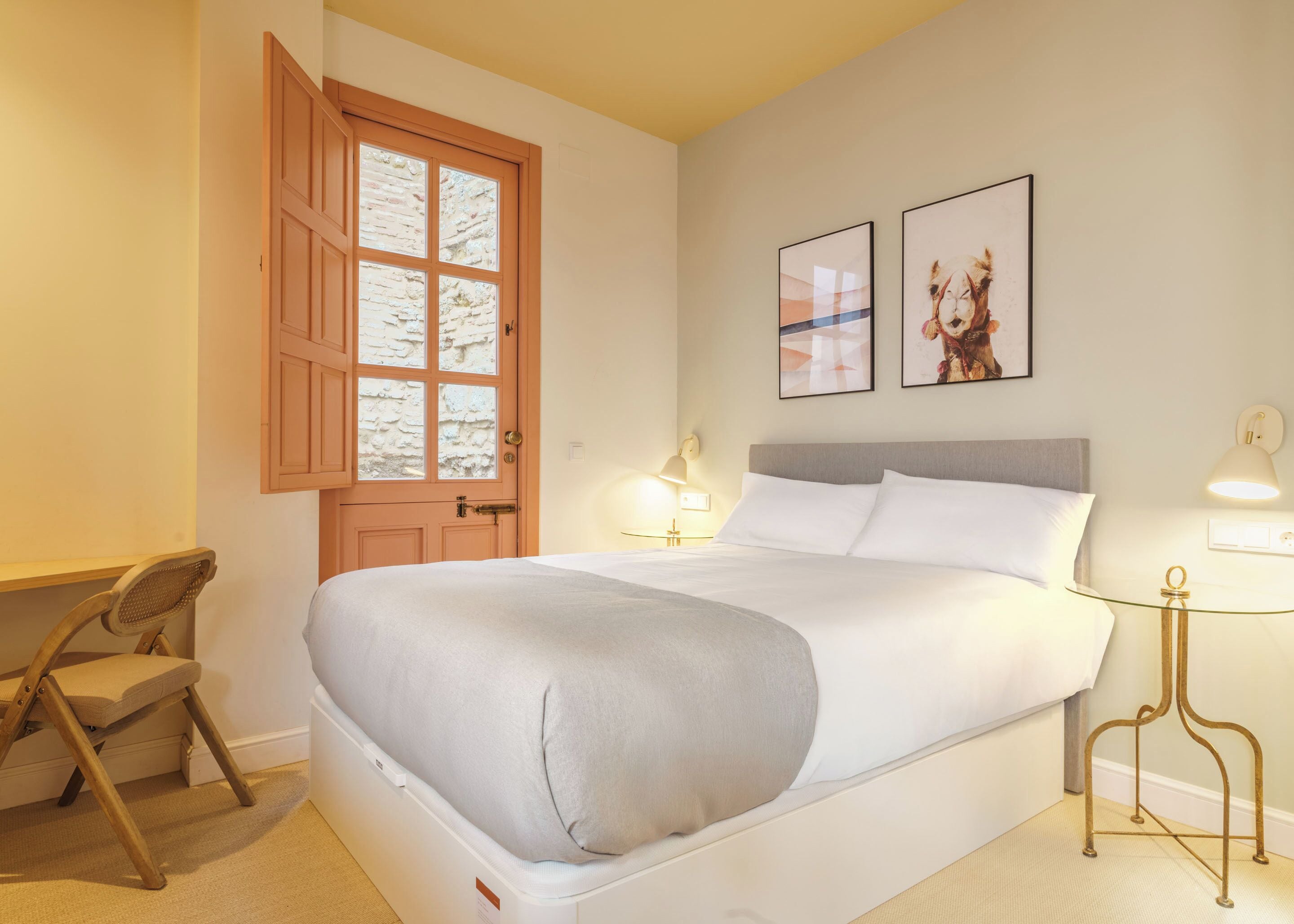 A neatly arranged hotel room with a bed, a desk, a chair, and a window with a view.