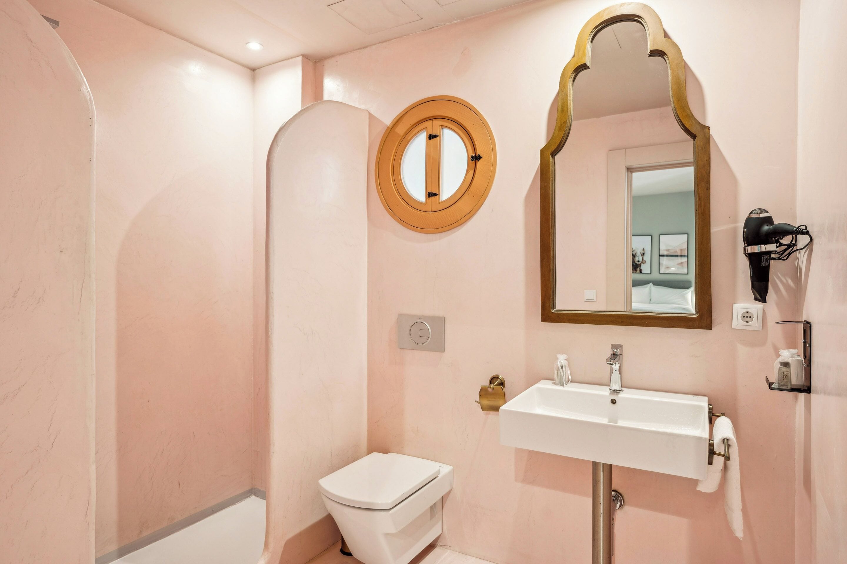 A bathroom with a white toilet, a sink, a mirror, and a shower.