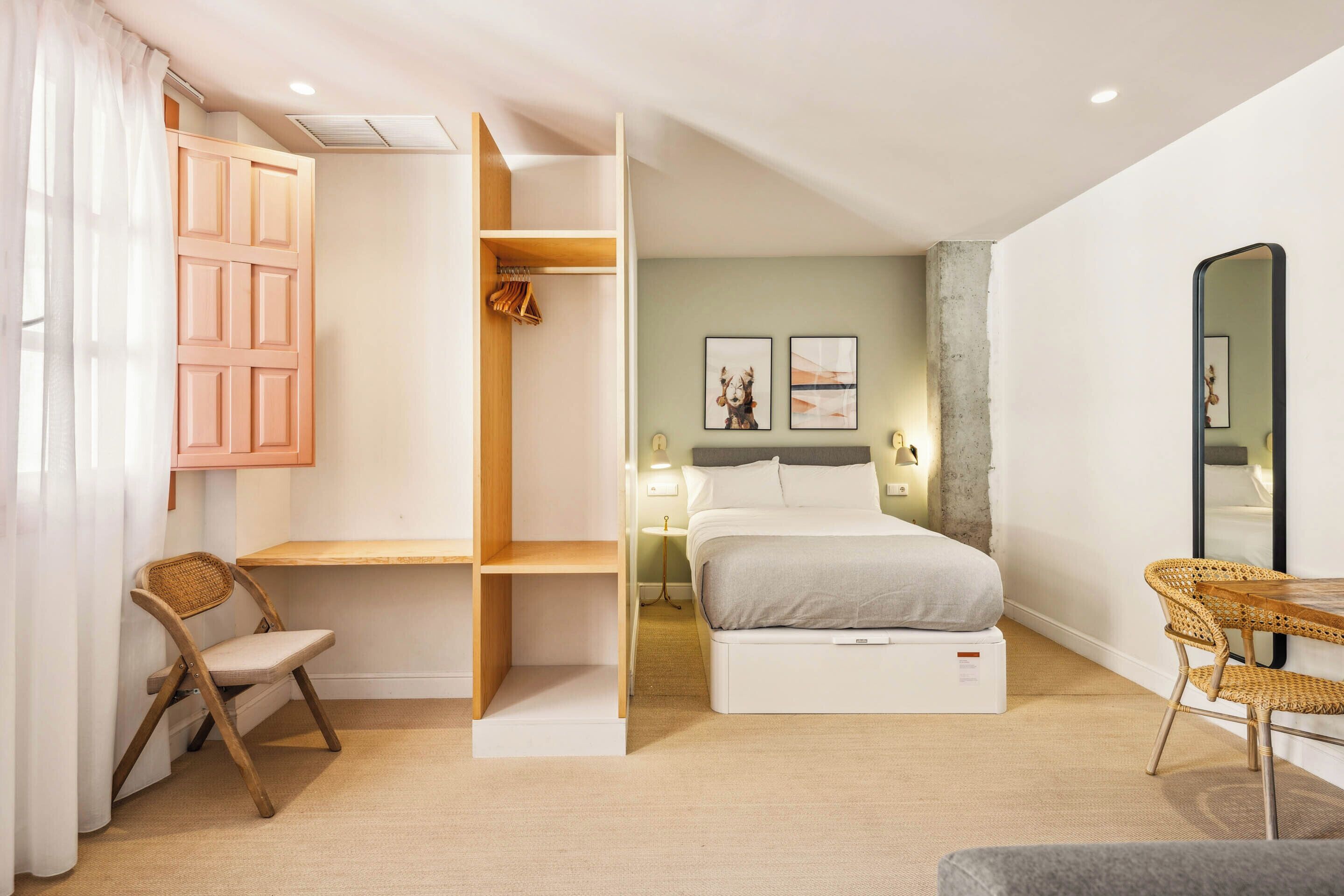 Une chambre à coucher comprenant un lit, un bureau, une chaise, une armoire et un miroir.