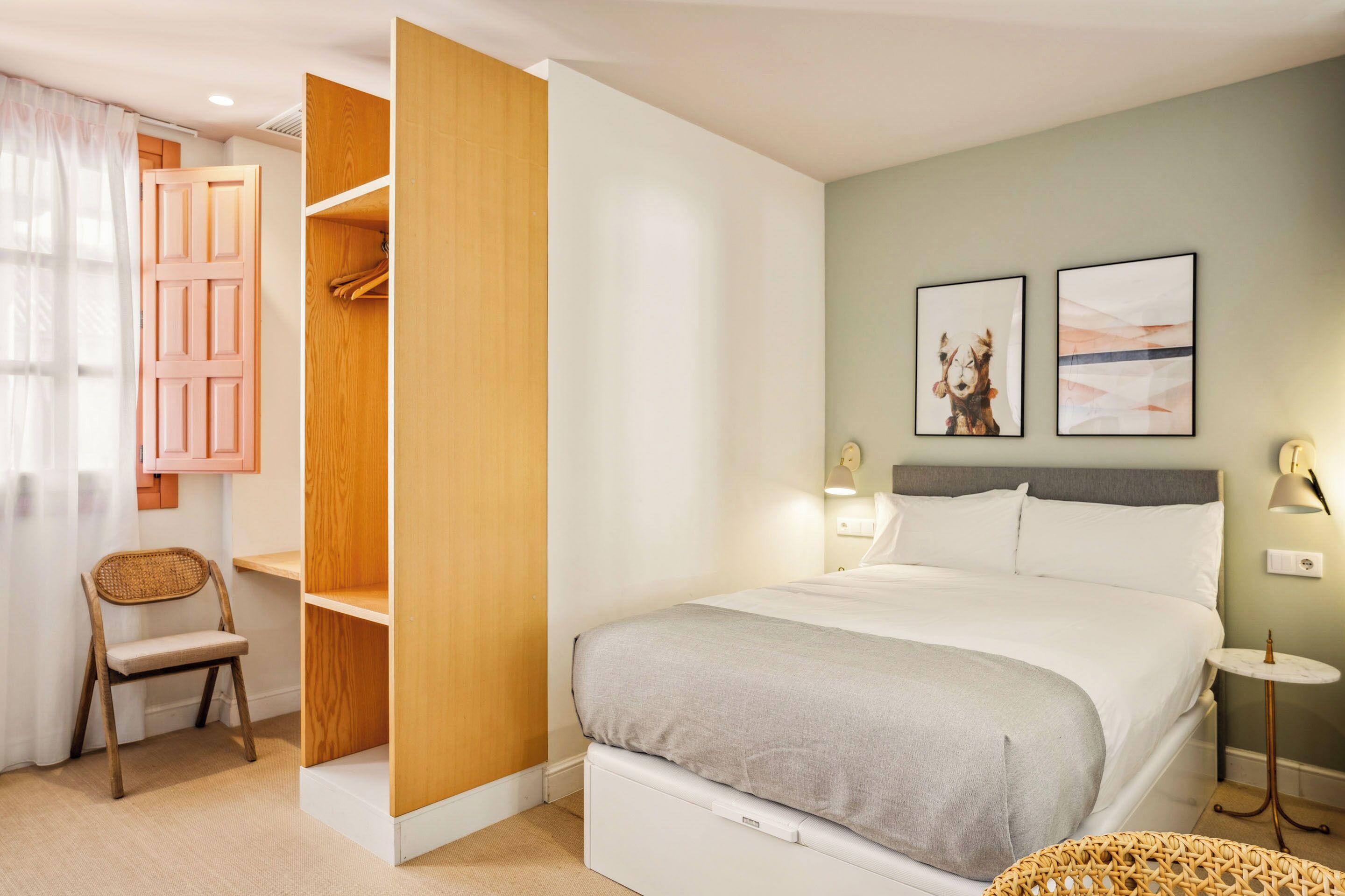 Une chambre à coucher comprenant un lit, une armoire, une chaise et deux lampes fixées au mur.