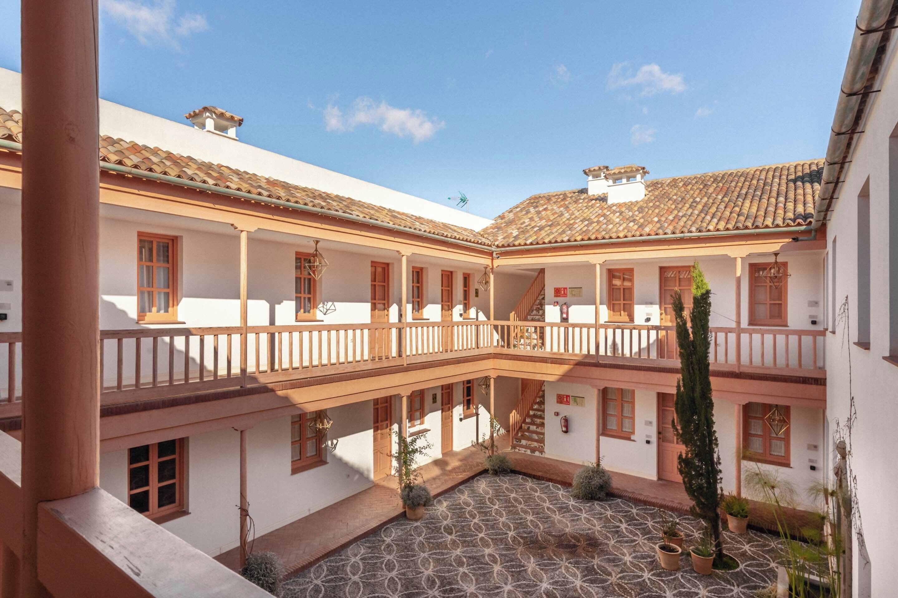 A courtyard with a tiled floor, white walls, and wooden balconies.