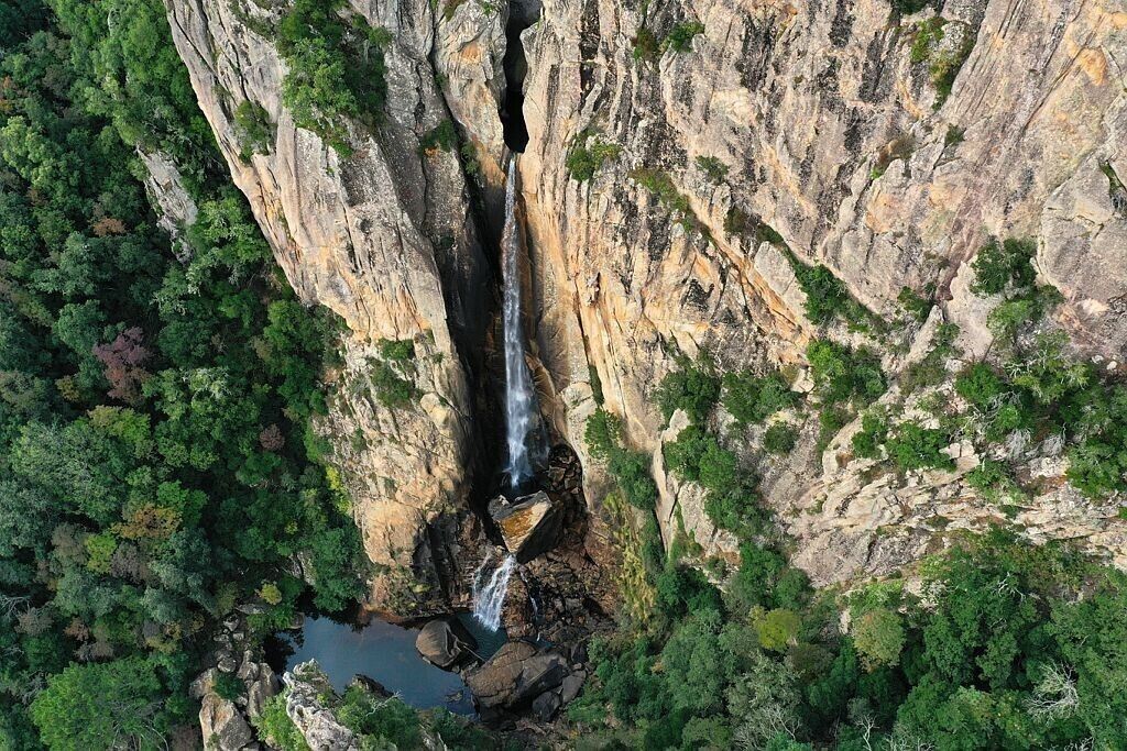 A waterfall cascading down a rocky cliff surrounded by dense forest.