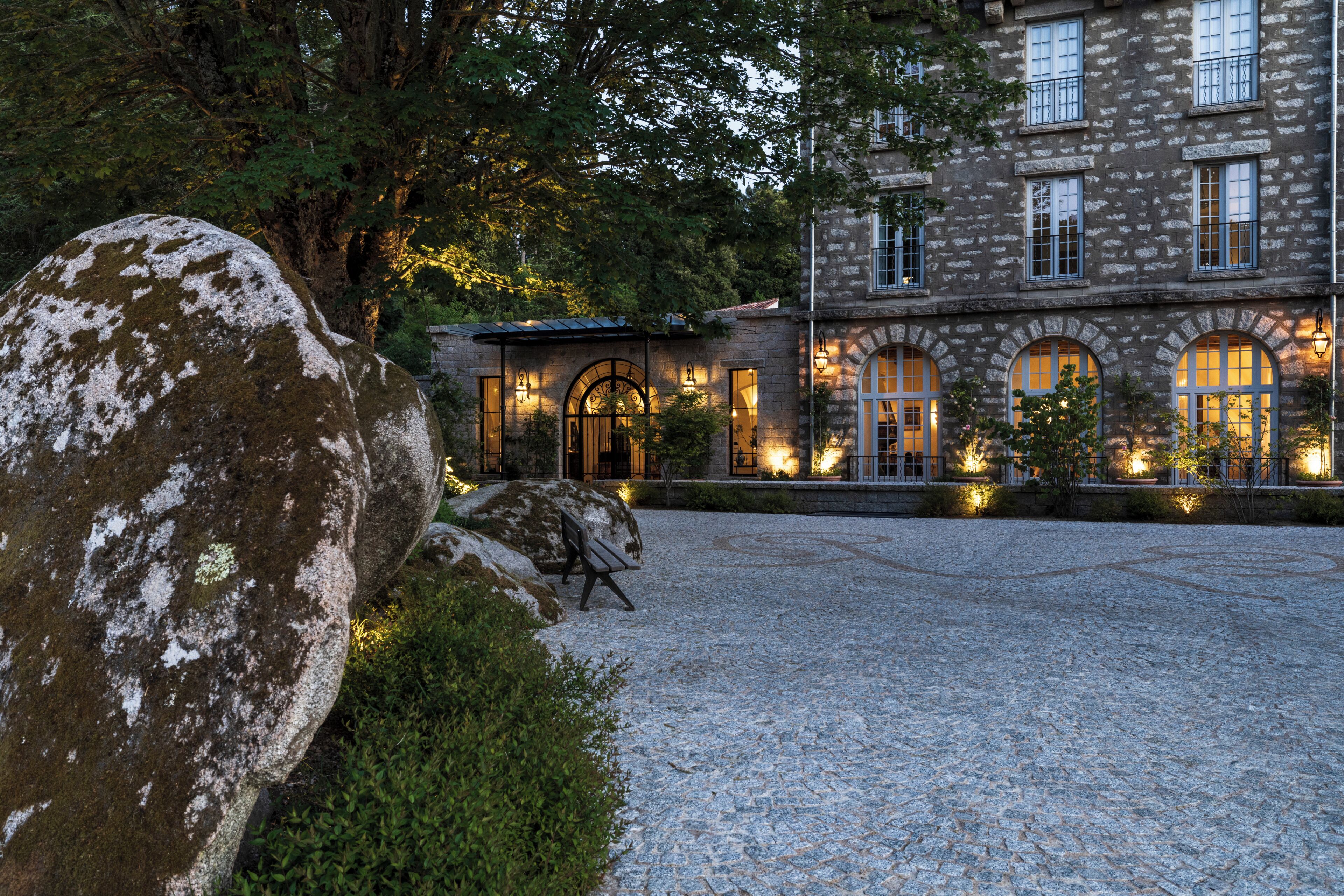 A stone building with arched windows and a gravel courtyard.