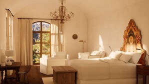A bedroom with a large bed, a chandelier, a view of the outdoors, and a decorative wall piece.