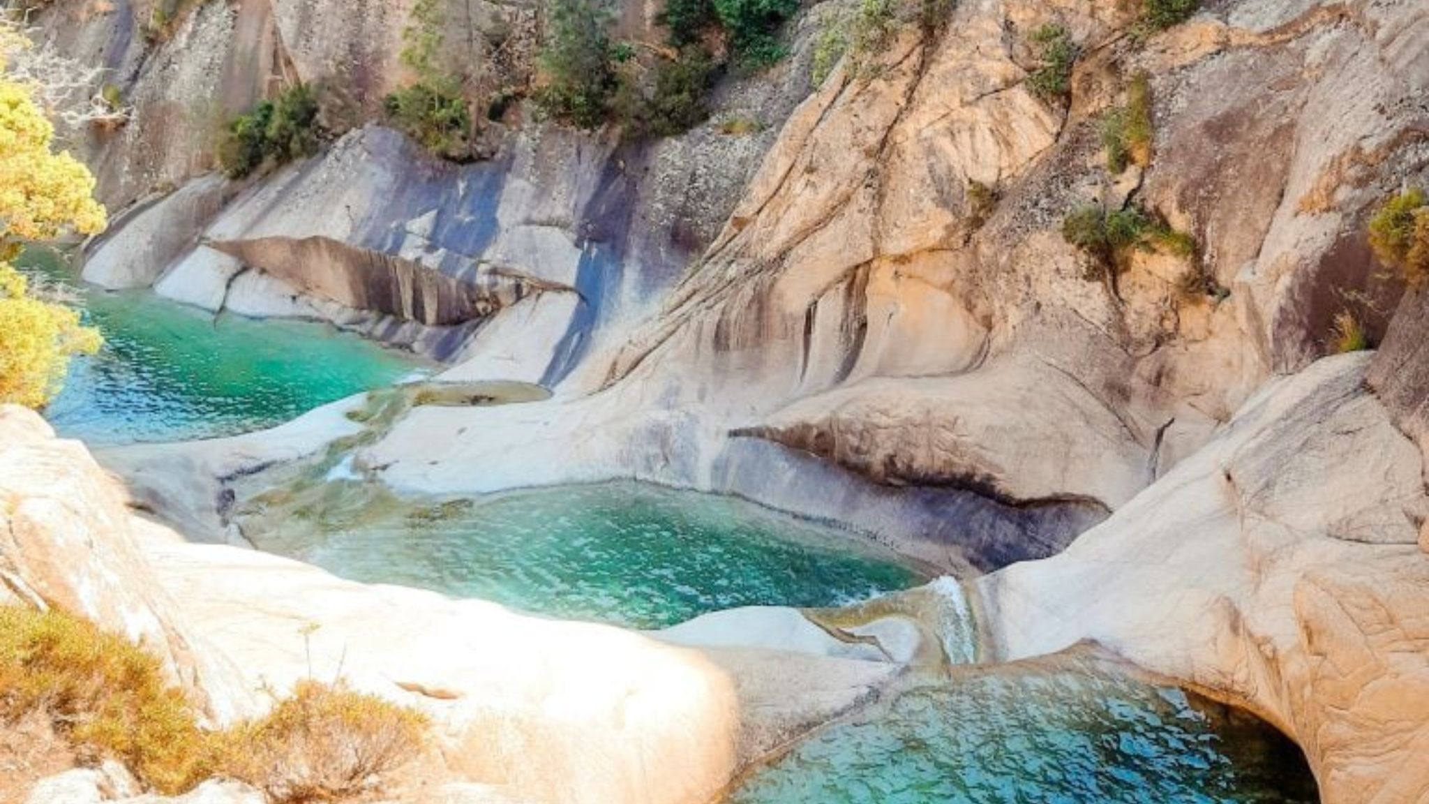 A natural hot spring area with clear water and rocky terrain.