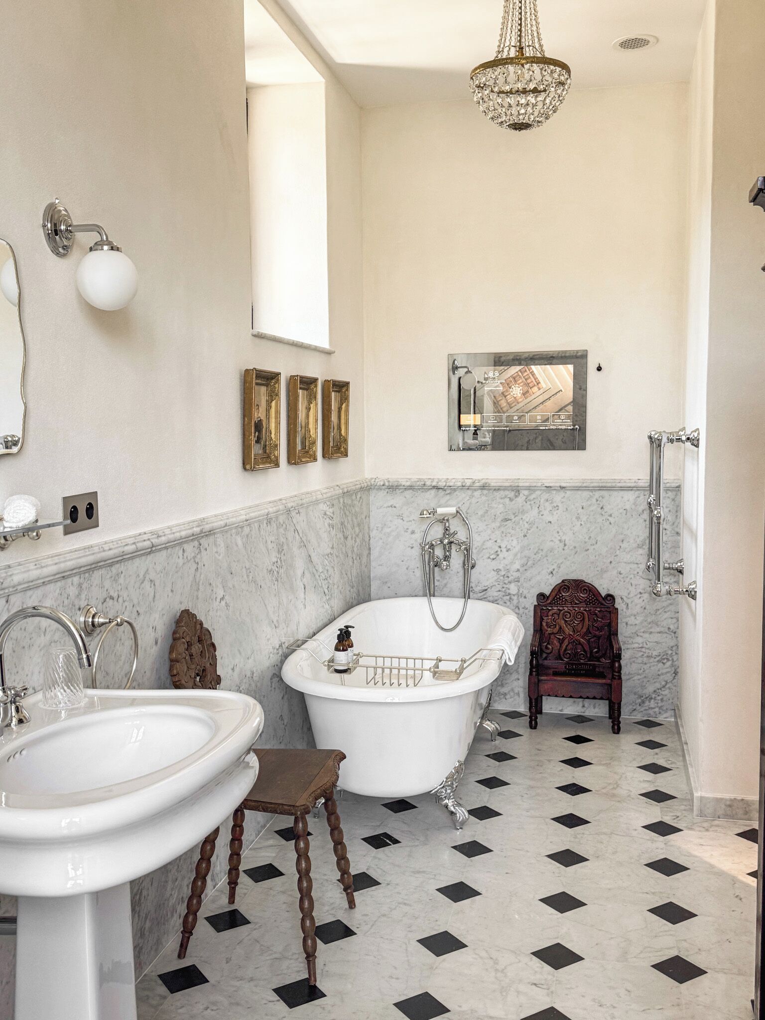 A bathroom with a freestanding bathtub, a pedestal sink, and a vanity mirror.