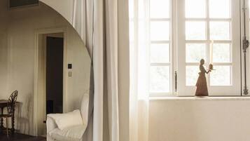 A room with a large window, a wooden table, and a mirror reflecting part of the room.
