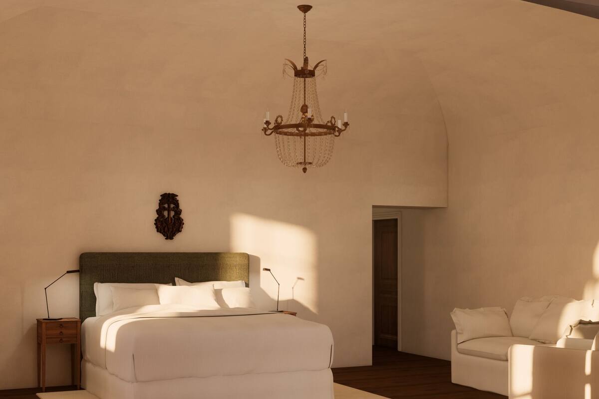 Een slaapkamer met een bed, nachtkastjes, een kroonluchter en een kunstwerk aan de muur.