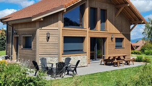 A wooden cabin with a sloped roof, large windows, and outdoor seating. - Nature Chalet with Sauna and WIFI near Gérardmer (Anould)