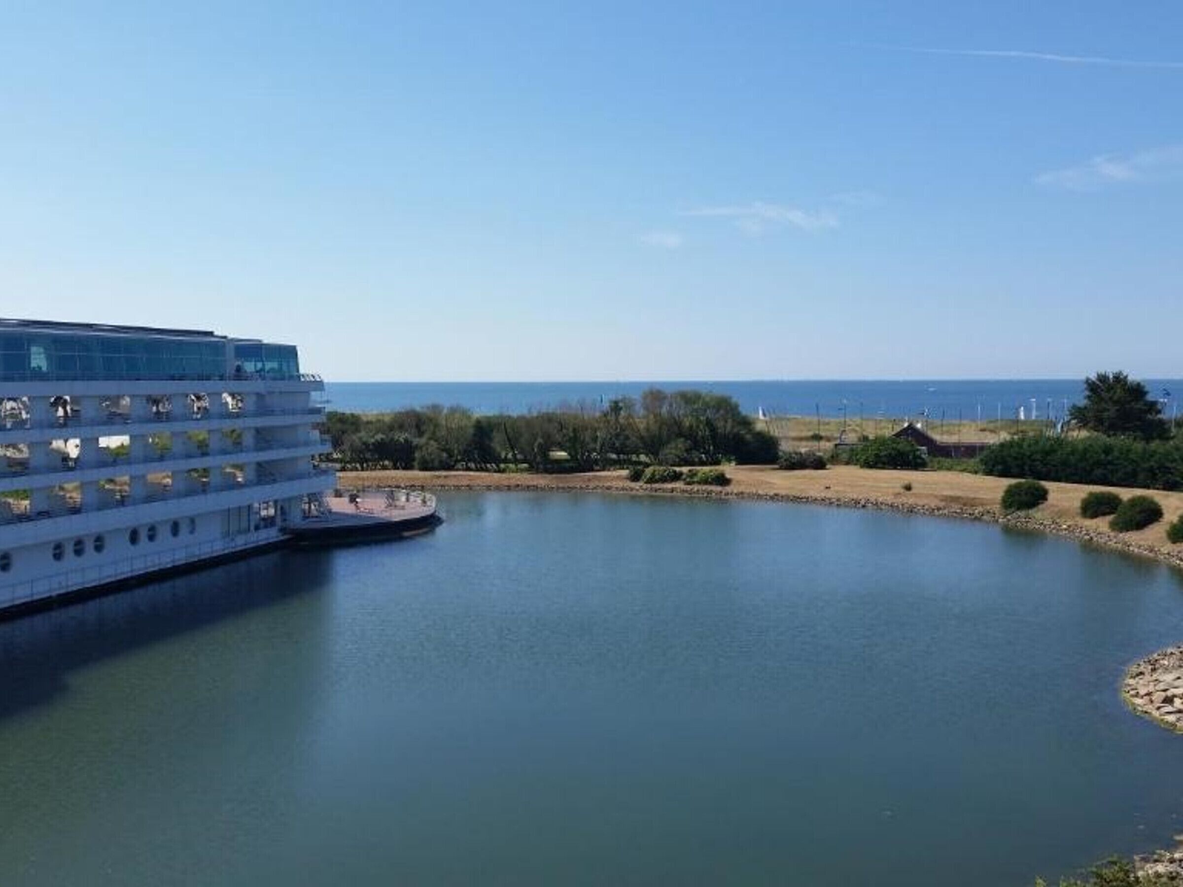A waterfront hotel with multiple balconies overlooking a calm body of water.