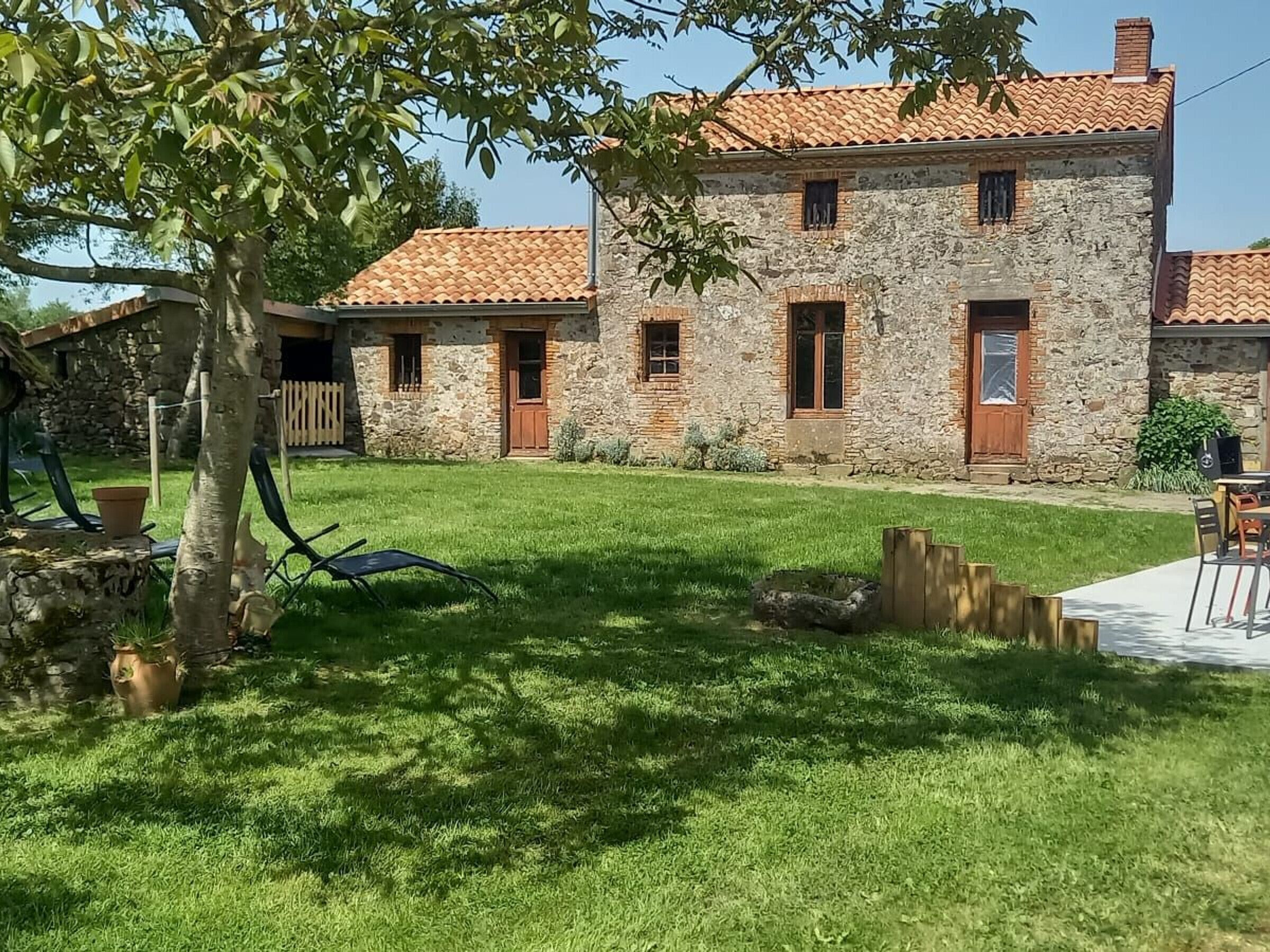 A stone building with a tiled roof, a grassy yard, and a wooden fence.