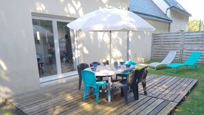 A wooden deck with a round table and chairs, an umbrella, and two lounge chairs. - House in Sarzeau, 3 bedrooms, near beach and shops, pets allowed, internet (Sarzeau)