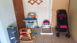 A room with a wooden rocking horse, a high chair, and a stroller. - Country Escape: Renovated Cottage with Pets Allowed (Saint-Bonnet-de-Four)
