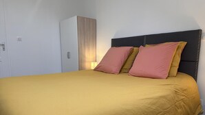 A bed with a yellow bedspread and two pillows, a wardrobe, and a wall-mounted light. - Country Escape: Renovated Cottage with Pets Allowed (Saint-Bonnet-de-Four)