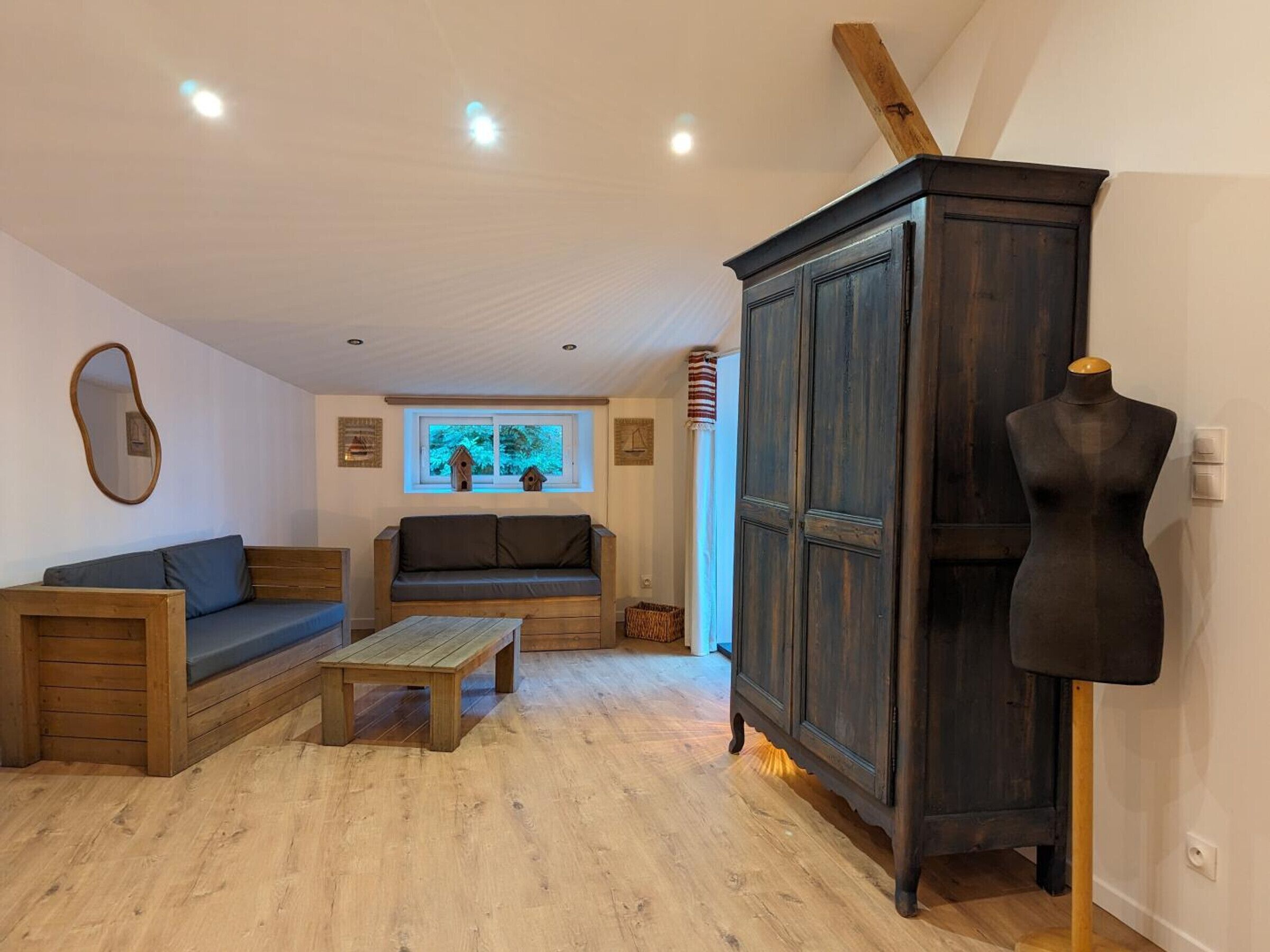 Un salon chaleureux avec un banc en bois, un canapé, une petite table et un buffet en bois foncé.