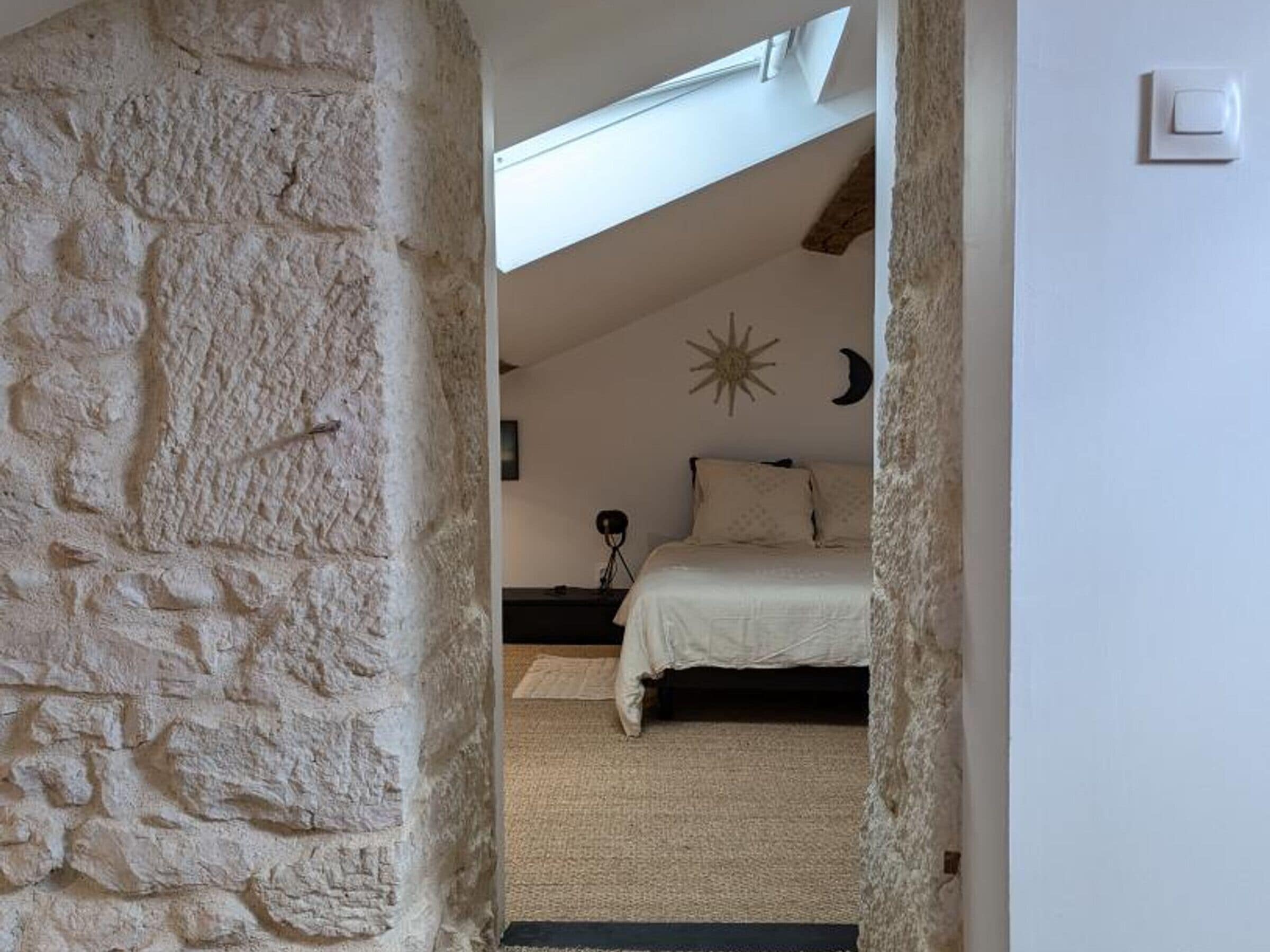 Ein Schlafzimmer mit Steinwand, einem Bett, einem Nachttisch, einer Lampe und einer Sterndeko an der Wand.