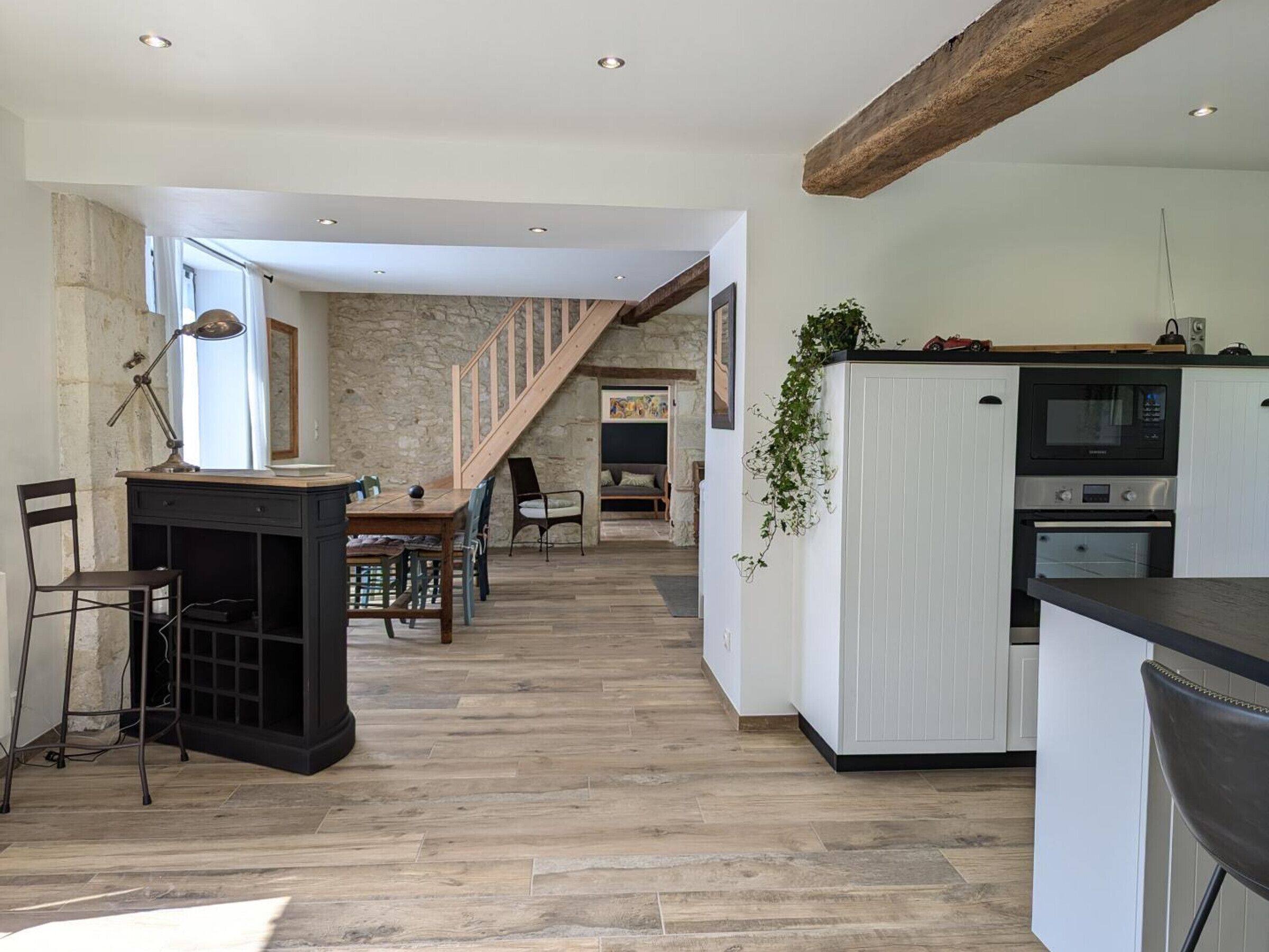 Une cuisine spacieuse avec un plancher en bois, des meubles blancs et un four encastré.