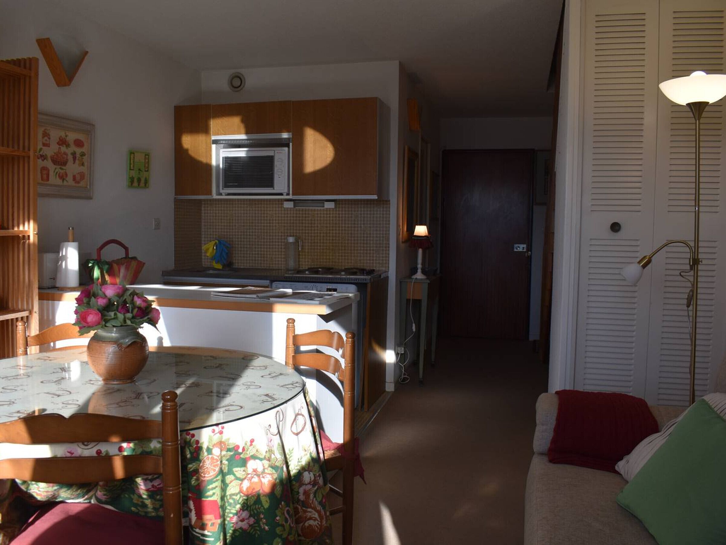 Uma cozinha compacta com micro-ondas, fogão e área de refeições com mesa e cadeiras.