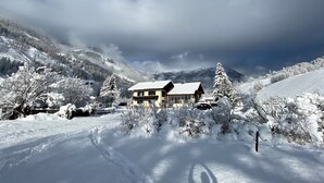 A snow-covered mountain landscape with a chalet-style building in the foreground.