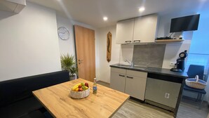 A compact kitchen with a wooden table, a sink, and a clock on the wall.