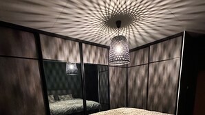 A bedroom with a bed, a hanging light fixture, and a patterned wall. - Kvaloysletta - 2 Bed Apartment - Free Parking (Tromsø)