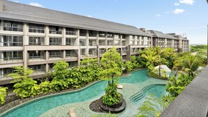 Un hotel con piscina rodeado de exuberante vegetación y una fachada de edificio moderna.