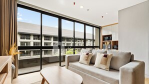 Una sala de estar moderna con un sofá, una mesa de centro y un ventanal con vistas a un edificio.
