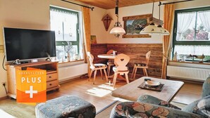 A cozy living room with a flat-screen TV, wooden furniture, and a dining area with a table and chairs. - Fewo "bei Tannenbaums", Oberstaufen (Oberstaufen)