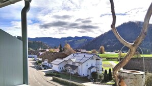 A view of a white building with a sloped roof, surrounded by greenery and a mountainous landscape. - Fewo "bei Tannenbaums", Oberstaufen (Oberstaufen)