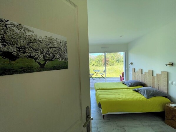 Una camera da letto con due letti, vista sull'esterno e porta che dà su un balcone.