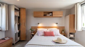 Un dormitorio moderno con una cama grande, mesitas de noche, un armario y estanterías empotradas.