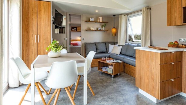 Un espacio habitable compacto con kitchenette, comedor y zona de estar con sofá y mesa de centro.