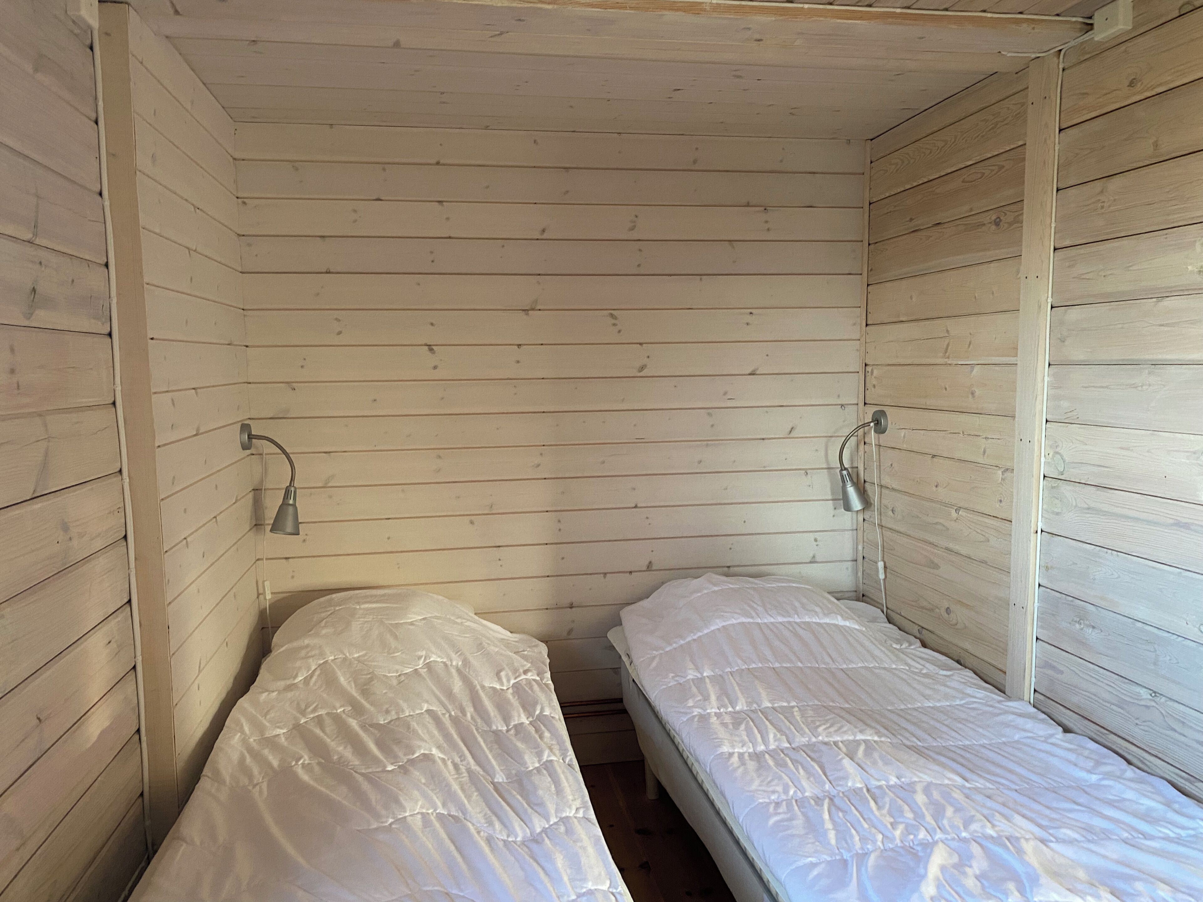 A small, single-room cabin with wooden walls and two beds.
