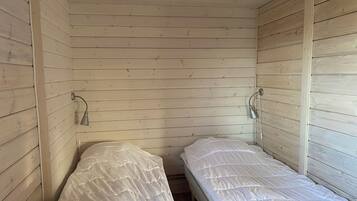A small, single-room cabin with wooden walls and two beds.
