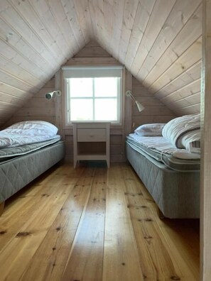 A small attic bedroom with two beds, a window, and a desk. - Kappelshamns Veranda (Lärbro)