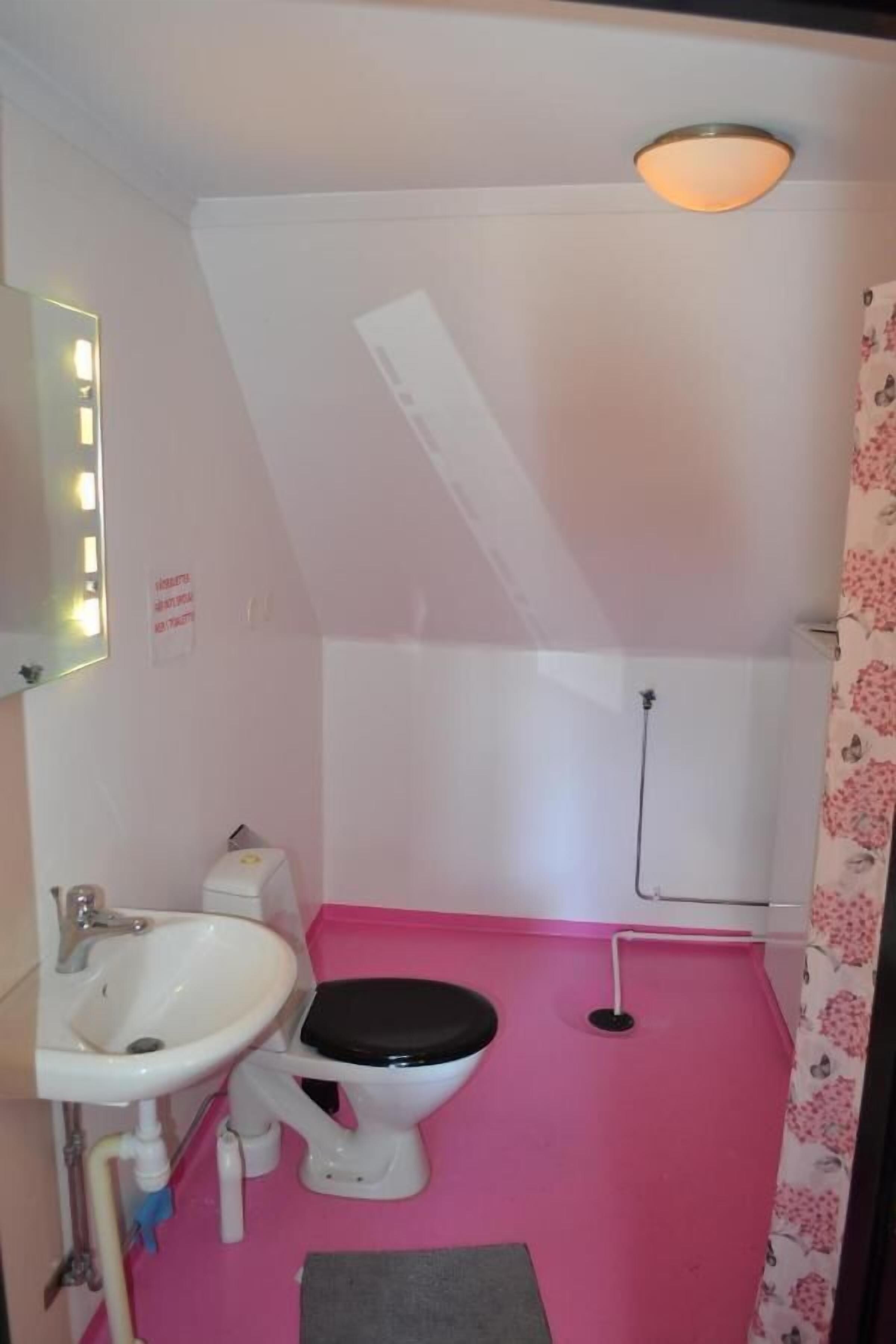 Un baño pequeño y funcional con un lavamanos blanco, inodoro y zona de ducha.