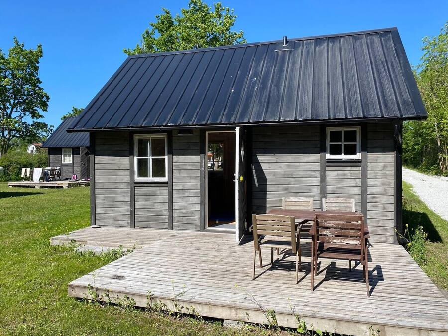 A wooden cabin with a metal roof, a deck, and a bench.